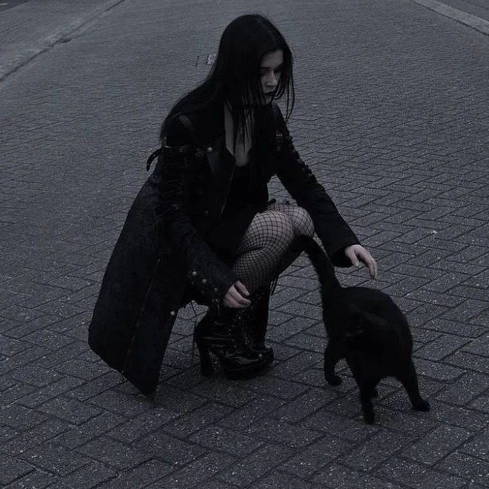 A girl crouching with a black cat